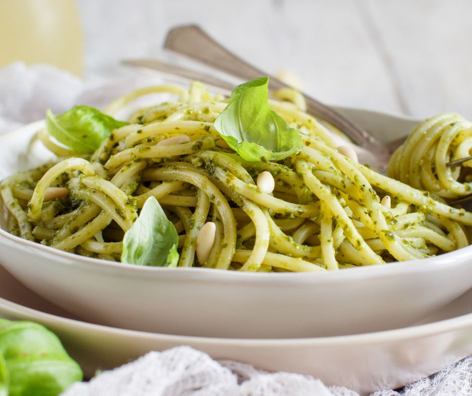 Tossing spaghetti with pesto sauce in skillet